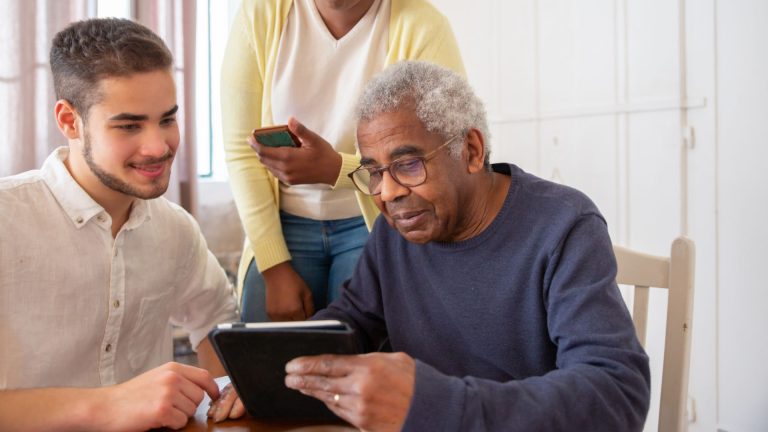 An occupational therapist educating an elderly man on an ipad during Occupational Therapy for Adults with Dementia session