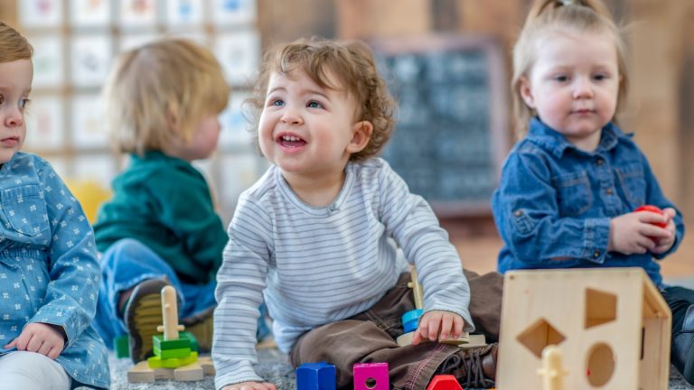 a toddler playing with several other toddlers