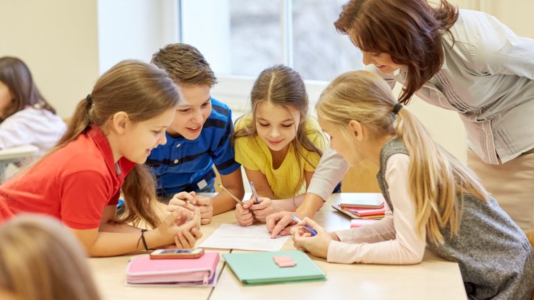 children and a teacher in primary school working on classwork