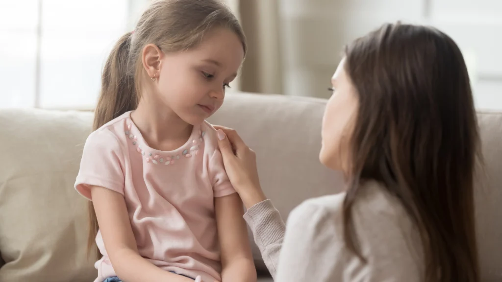 Parent kneeling at eye level to calmly talk with an upset young child at home